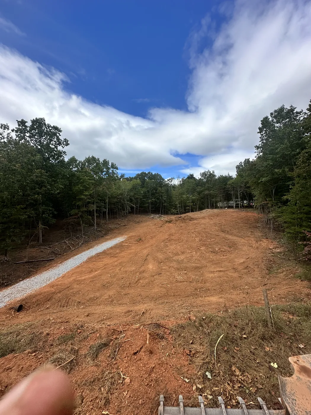 Gravel driveway through cleared lot with new construction at Cinnamon Ridge