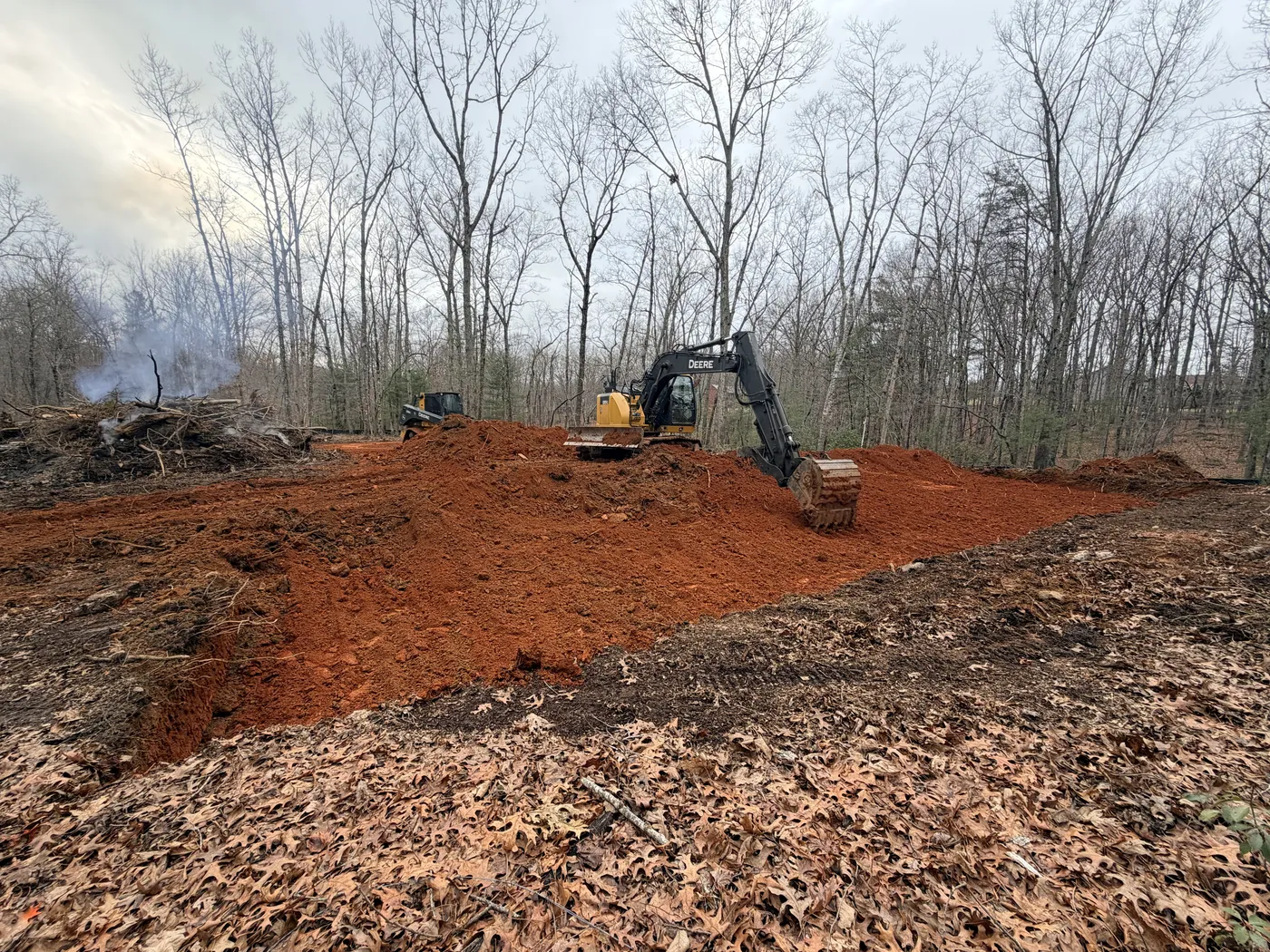 Excavator working on land clearing and grading for barndominium site