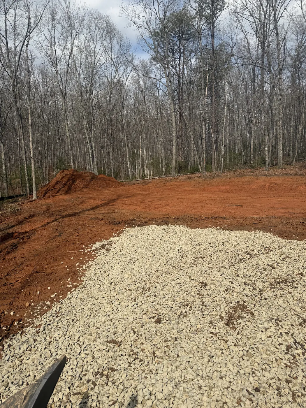 Gravel driveway and cleared building pad on wooded property
